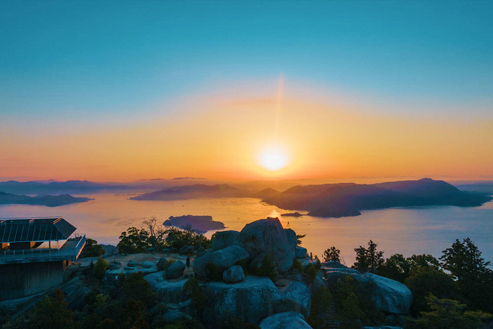 宮島・弥山山頂の巨岩群と展望台から望む、夕日に染まる瀬戸内海の島々。